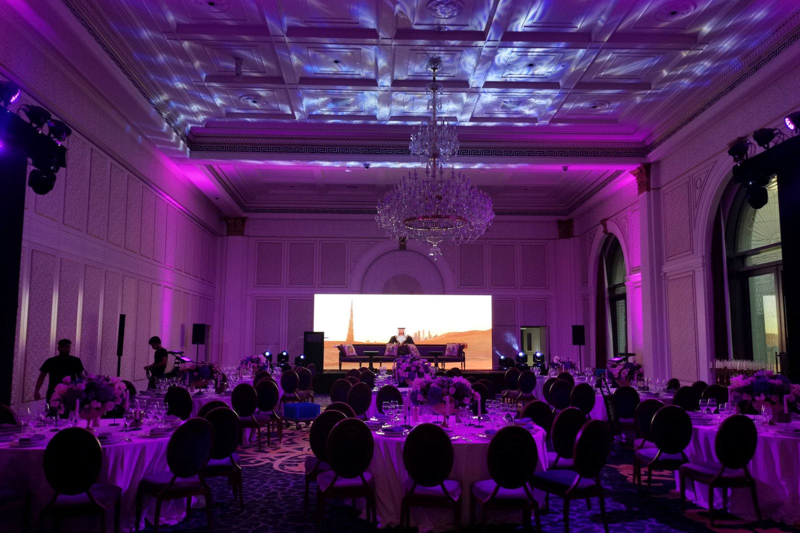 Round tables dressed and facing the stage in a ballroom